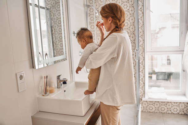 istock Woman holding her child while applying moisturizer at her face 1325207981