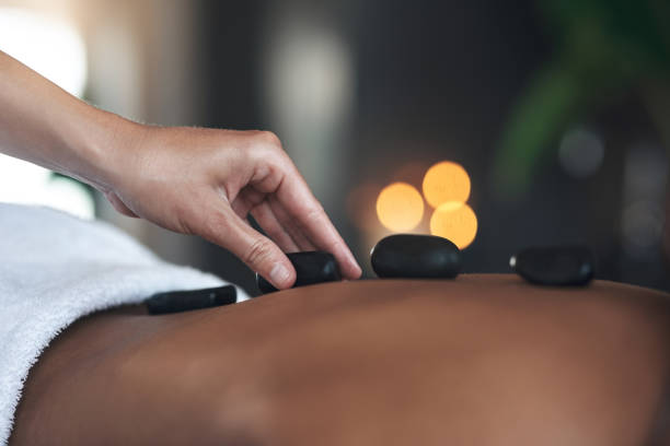 nahaufnahmen einer nicht wiederzuerkennenden frau, die eine hot-stone-massage in einem spa bekommt - massaging spa treatment stone massage therapist stock-fotos und bilder