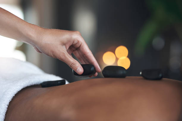 nahaufnahmen einer nicht wiederzuerkennenden frau, die eine hot-stone-massage in einem spa bekommt - massaging spa treatment stone massage therapist stock-fotos und bilder