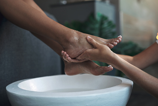 Woman soaking her feet in bowl with water, closeup. Pedicure procedure