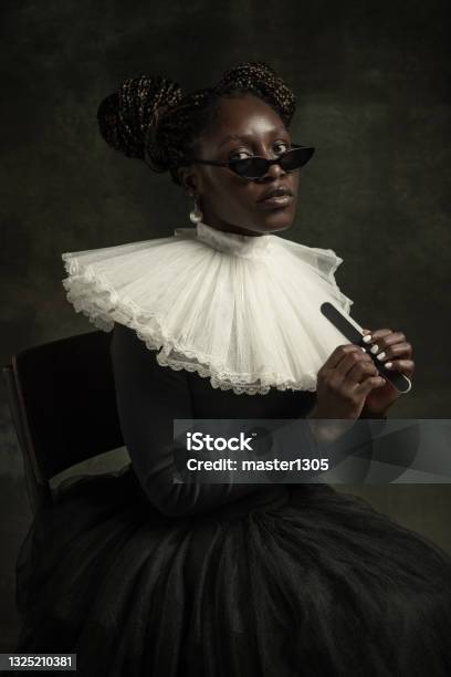 Portrait Of Medieval African Young Woman In Black Vintage Dress With Big White Collar Posing Isolated On Dark Green Background Stock Photo - Download Image Now