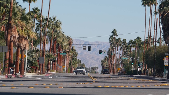 Palm Springs, California USA - 20 Dec 2020: Street traffic, cars driving on road, transport in city near Los Angeles. Palm Canyon drive. Summer vacations resort, oasis in desert valley in mountains.