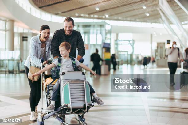 Couple Pushing Trolley With Their Child At Airport Stock Photo - Download Image Now - Travel, Family, Airport