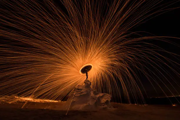 Steel wool photography at the desert rock structure at night time with fire splash all over. Slow Shutter speed photography with steel wool