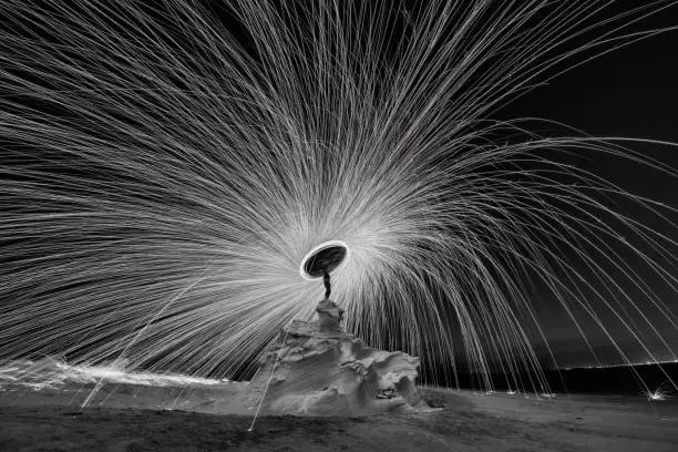 Steel wool photography at the desert rock structure at night time with fire splash all over. Slow Shutter speed photography with steel wool in black and white