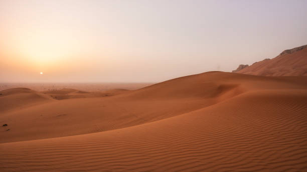 istock Beautiful desert sunrise with sun visible and sand dooms with sand pattern 1325223049
