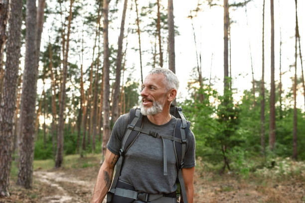 istock Smiling mature caucasian man walking alone in forest 1325223331