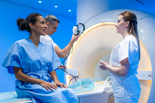 Female doctor giving information to woman before MRI scan examination. Magnetic resonance imaging technology in specialized medical clinic.