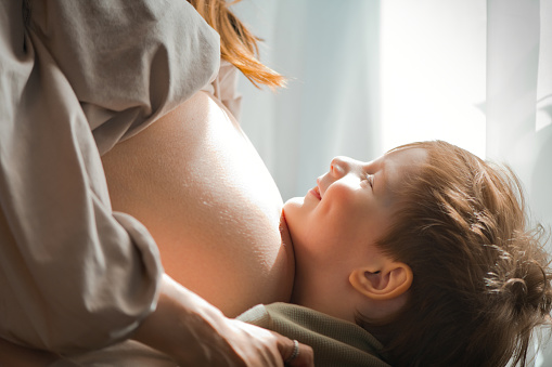 Beautiful woman showing pregnant belly yo her daughter