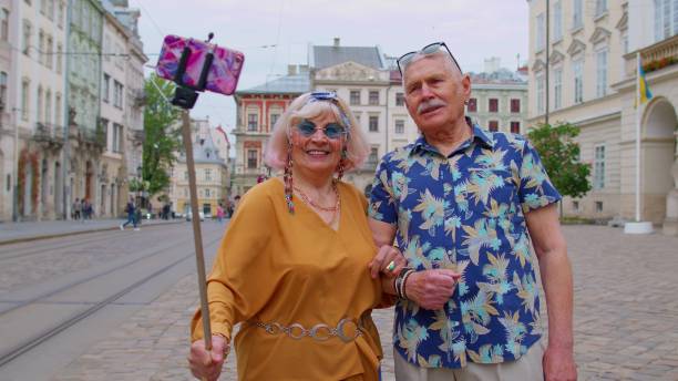 senior stilvolle blogger touristen mann frau macht selfie-foto, machen videoanruf auf dem handy - einbeinstativ stock-fotos und bilder