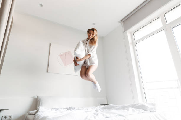 istock Happy pretty woman jumping with pillow 1325226724