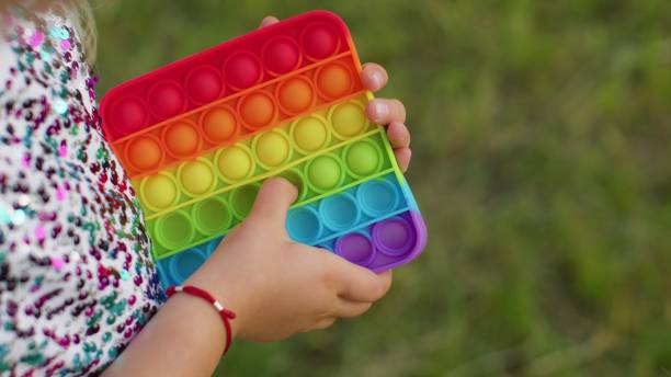 niña jugando burbujas de silicona blandas de colores sensoriales de pie simple hoyuelo pop it juego, primer plano - child sensory perception expressing negativity human hand fotografías e imágenes de stock