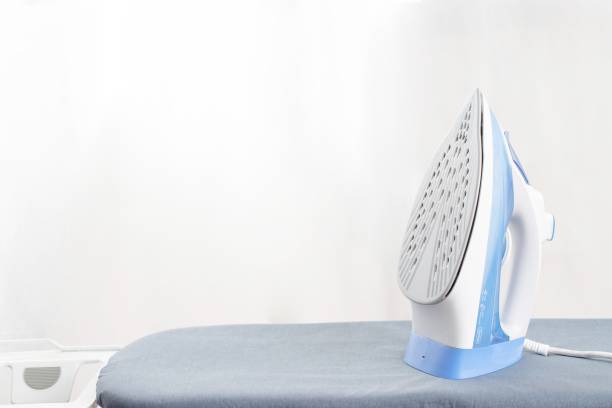 An electric iron and put the clothes on the ironing board. stock photo