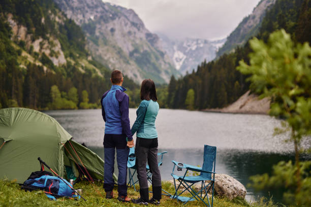 istock Affectionate couple relaxing near a lake while camping 1325229565