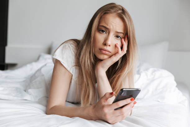 istock Sad woman lies on bed indoors looking camera. 1325229969