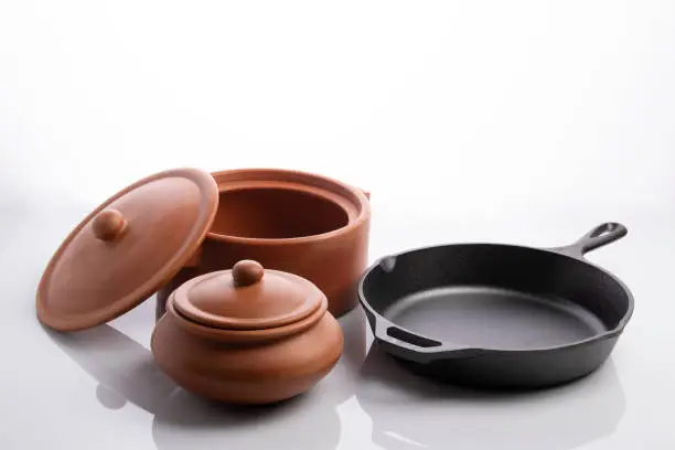 High resolution image of terracotta pots and cast iron skillet on white background shot in studio