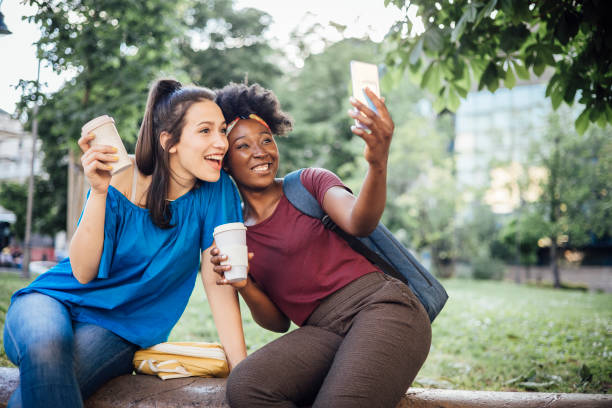 istock Two female students having fun, taking selfies and enjoying coffee in the park 1325236496