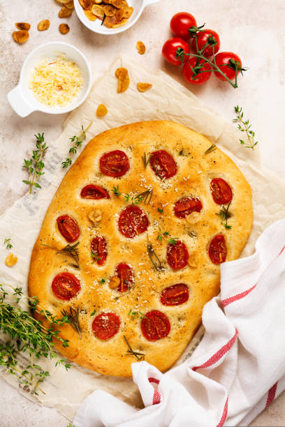 italienisches traditionelles focaccia-brotbacken mit kirschtomaten, parmesan und rosmarin auf hellbraunem hintergrund. draufsicht - italian cuisine gluten free food tomato herb stock-fotos und bilder