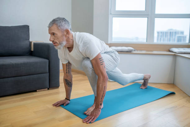 istock A mature man practising yoga at home and looking concentrated 1325239977
