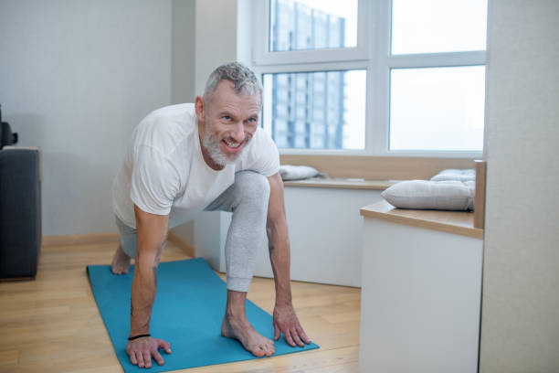 istock A mature man practising yoga at home and looking concentrated 1325239981