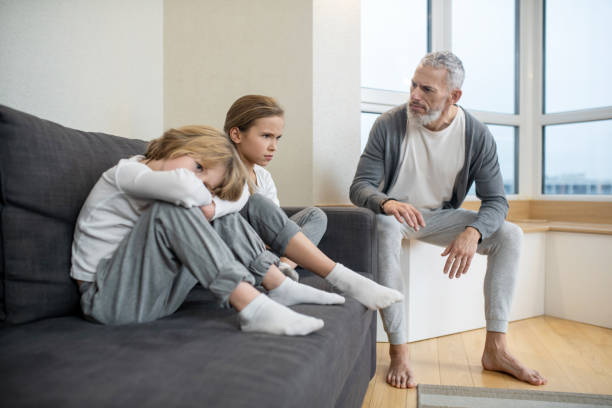 istock Gray-haired bearded man talking to his kids while they looking moody 1325240146