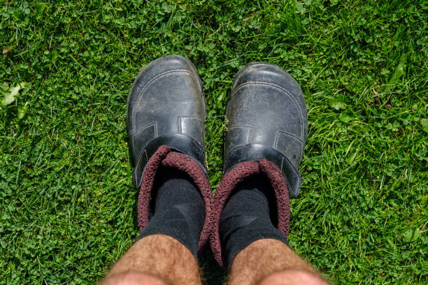 istock Men's hairy legs in socks and old galoshes. 1325242642
