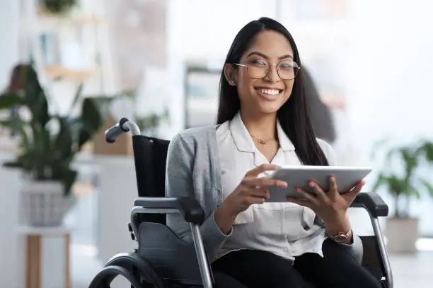 Photo of Cropped portrait of an attractive young businesswoman in a wheelchair using her tablet in the office