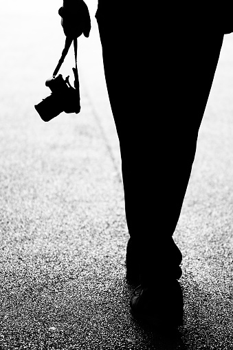 Low-section of silhouette of legs of man with camera