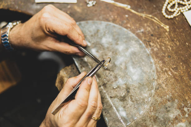 istock Jeweler working in his workshop placing a gem on a gold ring 1325248220