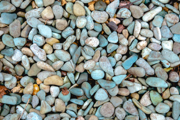 Background from small stones of different sizes, turquoise-blue hue, with smooth sides. Items are scattered randomly, top view.