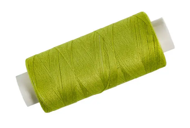 Spool of thread light green on white isolated, home creativity or needlework.