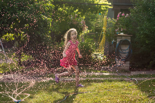 istock Child playing with garden sprinkler 1325248897