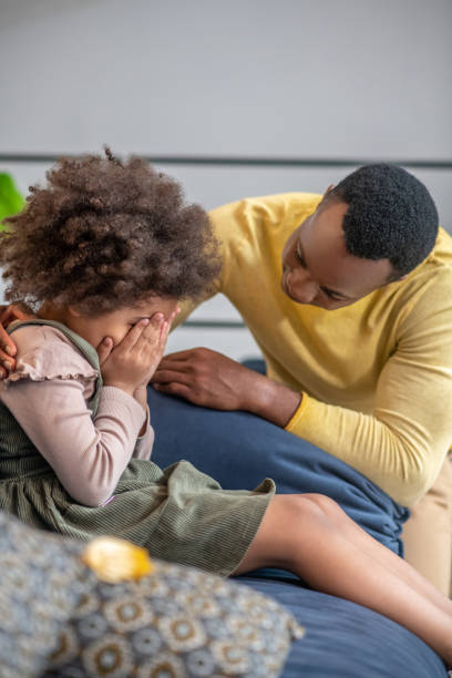 istock Little girl hiding her face and attentive dad 1325250190