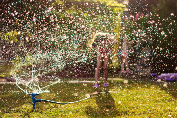 istock Children play with hose watering flowers 1325250346