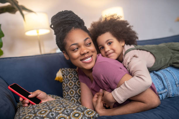 istock Happy darkskinned mom with daughter lying on sofa 1325250439