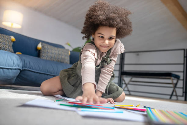 istock Little girl choosing colored pencil on floor 1325250577
