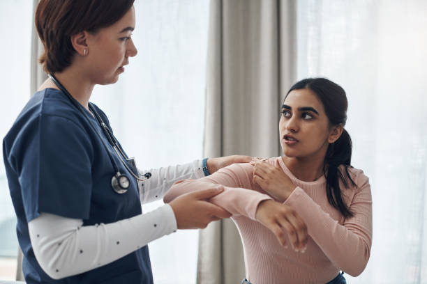 colpo di una giovane dottoressa che controlla il braccio di una paziente in un ufficio - patient doctor male talking foto e immagini stock