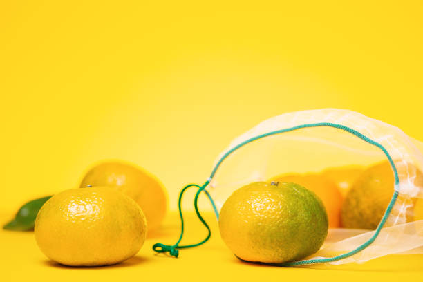 istock Eco-friendly. Fresh tangerines in reusable eco friendly mesh bag on yellow background. Copy space. Concept of zero waste 1325253024