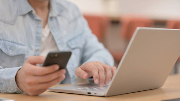 istock Male Hands using Smartphone while Typing on Laptop, Close up 1325256554
