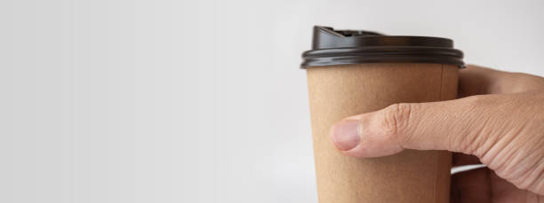 Close up, Man Hand Holding Brown Paper Coffee Cup Isolated on Gray Background, Mockup Paper Coffee Cup.
