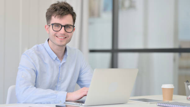 istock Young Man with Laptop Smiling at Camera 1325258234