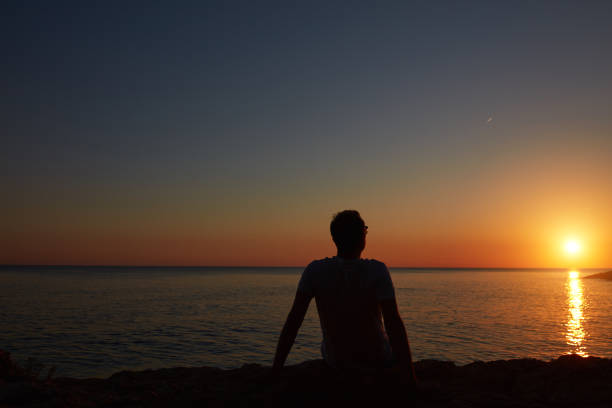 istock Silhouette of a man watching sunset over distant horizon. 1325258382