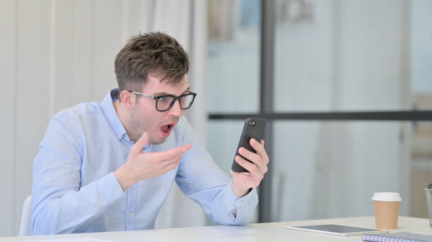 istock Young Man Reacting to Loss on Smartphone in Office 1325259070