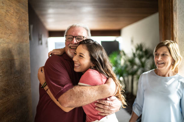 granddaughter embracing grandfather at home - grandparent senior adult senior women multi generation family imagens e fotografias de stock