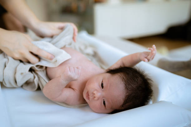 istock Mother taking off clothes her newborn baby before bathing. 1325263570