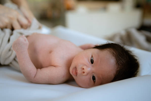 istock Mother taking off clothes her newborn baby before bathing. 1325263573