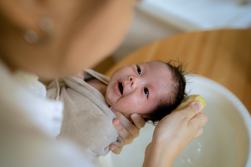Young Asian mother cleaning hair her daughter during bathing.