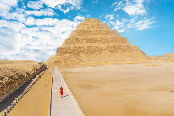 una ragazza con un vestito rosso che cammina nella piramide a gradini di djoser, saqqara. egitto. la necropoli più importante di memphis. la prima piramide al mondo - saqqara foto e immagini stock