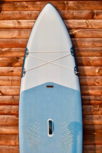 istock Paddleboard and surf board with paddle on brown wooden wall background close up 1325264675