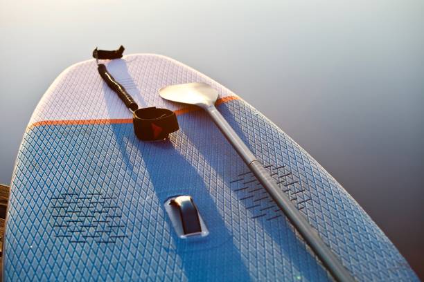 istock surf board with paddle in sunset light on blue water surface background close up 1325264848